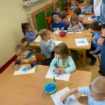 Grupa dzieci siedząca przy stolikach podczas pracy