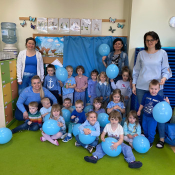 Zdjęcie grupowe dzieci ubranych na niebiesko trzymająca niebieskie balony z paniami